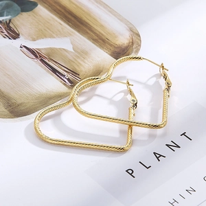 Polished gold heart-shaped hoop earrings with spiral twist texture on minimalist background