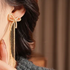 Elegant 18k gold plated bow tassel earrings with sparkling cubic zirconia on a model
