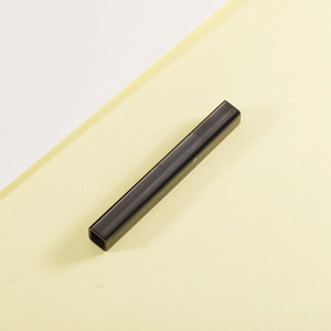 Close-up of a matte black hollow stainless steel tube accessory on a geometric background