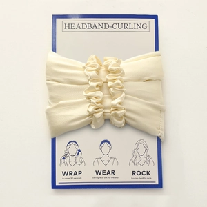 Macro shot of beige silk heatless curling headband with instructions on the card packaging