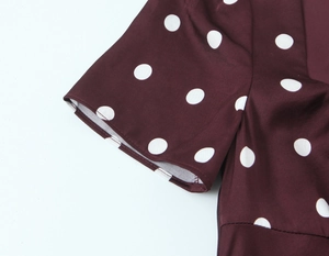 Detailed close-up of stitching and fabric on a burgundy polka dot elegant dress