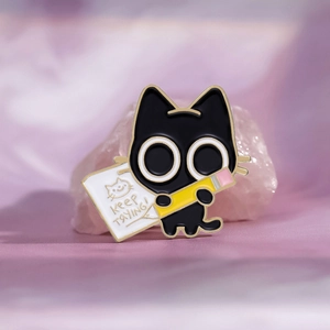 Cute black cat enamel pin holding a pencil with keep trying text on pink crystals