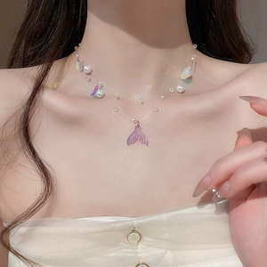 Detail of a pearl necklace with iridescent shell fishtail pendant on a female model