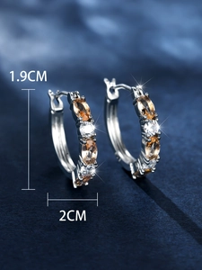 Detailed view of silver huggie hoop earrings with amber stones measuring 1.9cm by 2cm