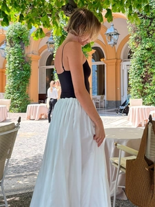 Detail of elegant high-waisted pleated white maxi skirt with a fluid drape finish