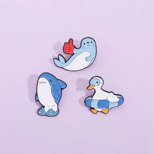 Three-piece set of cartoon shark seal and duck enamel pins on a light purple background