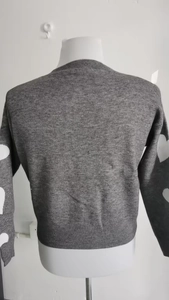 Detail view of the gray knitted cardigan sleeve featuring white heart pattern decorations