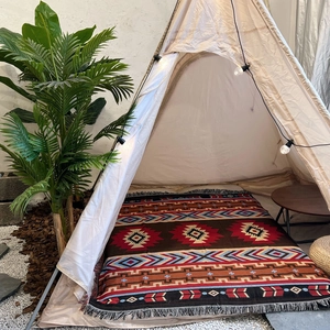Bohemian geometric camping blanket with tassels in a cozy outdoor tent setting