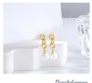 Detail of drop earrings with triple golden links and a round white pearl pendant