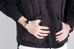 Detail of men's multilayer black braided leather bracelet with vintage silver hammer charm