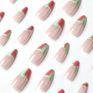 Press-on nails featuring orange-red and green geometric designs on almond shape