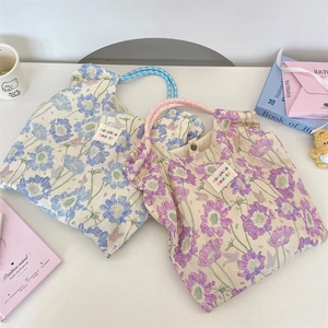 Detailed view of floral canvas tote bags with woven handles and brand woven labels
