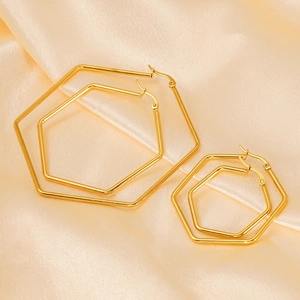 Créoles hexagonales polies en or 18 carats en deux tailles sur un tissu satiné champagne