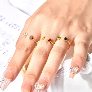 Close-up of six gold rings with colorful rectangular gemstones on hand with music sheet