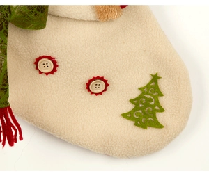 Detail of Christmas stocking featuring beige fleece fabric, wooden buttons and green tree