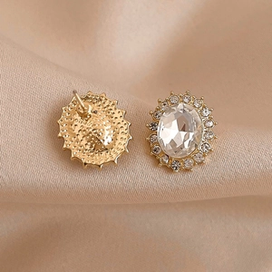 Élégantes boucles d'oreilles ovales dorées avec cristal clair et halo sur tissu en soie