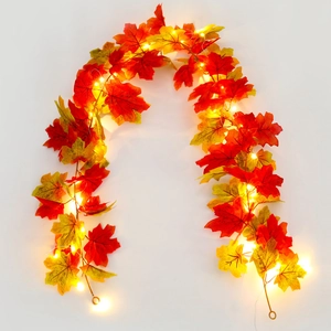 Detail of autumn maple leaf LED garland with warm lights and pine cones for home decor