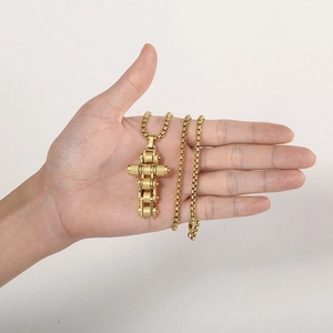 Macro shot of gold bicycle chain cross pendant on a square pearl box chain