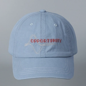 Close-up of red Opportunity letter embroidery on washed cotton blue baseball cap