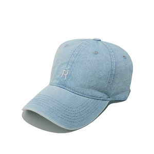 Detail view of the embroidered white R letter on a light blue denim baseball cap