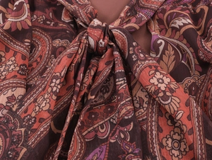 Detail of red paisley chiffon dress featuring a bohemian neck tie and textile texture