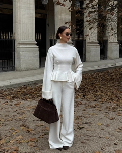 Vue street style d'un ensemble en tricot blanc avec pantalon large et sac en daim marron