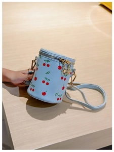 Detailed top view of light blue cherry print bucket bag with gold flower zipper pull