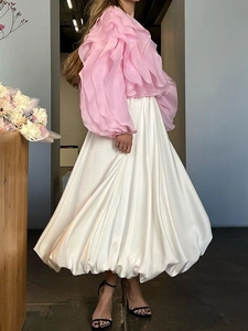 Roze ruches blouse en witte glanzende midi-rok in een minimalistische kamer