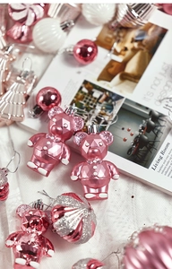 Pink geometric bear and glitter ornaments set on white textured fabric for tree decor