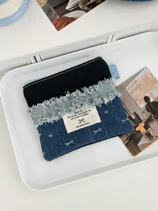 Denim bow storage bag with fringe trim for lipstick and coins on a white tray