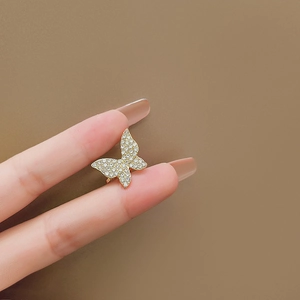 Détail macro du耳 cuff papillon doré avec zircons étincelants sertis en micro-pavage