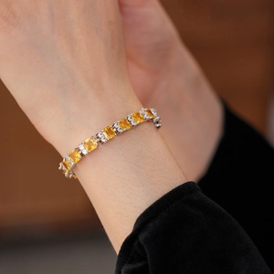 Detalle de una pulsera de plata con gemas amarillas cuadradas y circonitas en la muñeca