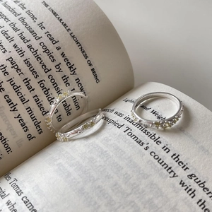 Three minimalist S925 sterling silver rings with yellow crystals on open book pages