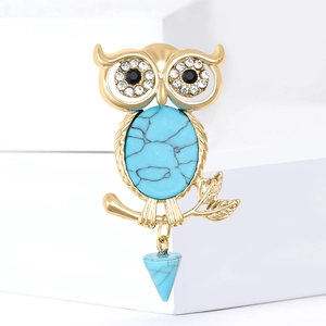 Retro golden owl brooch with turquoise stone inlay and crystal eyes on white background