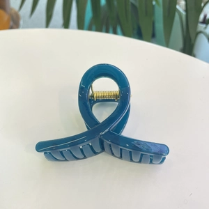 Détail d'une pince à cheveux en résine bleu foncé avec un ressort en métal doré