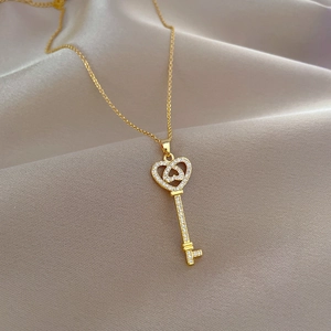 Luxury heart key necklace in gold finish with sparkling crystals on beige silk background