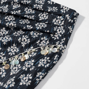 Vue macro détaillée du tissu floral bleu marine avec pompons en coquillages et perles