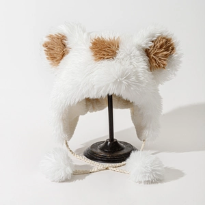 Close-up of white plush earflap hat with brown patches and soft faux fur pompoms