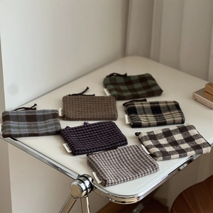 Detailed grid of assorted wool plaid mini coin purses with zipper closure and woven label