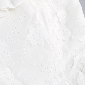 Detail shot of white floral lace embroidery with delicate hollowed-out craftsmanship