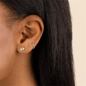 Golden Evil Eye earring set with blue zircon crystals shown on a female model's ear