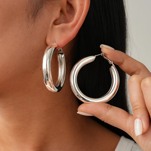 Macro detail of large silver hoop earrings with a thick polished metallic finish