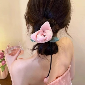 Detail of pink fabric rose hair clip with green leaves and long elegant tassels