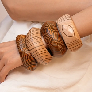 Detailed view of irregular geometric wooden bangles with rivet textures on a wrist