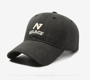 Close-up of dark grey denim baseball cap with white embroidered N GRACE logo detail