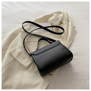 Detail of black lychee grain leather crossbody bag with top handle and flap closure