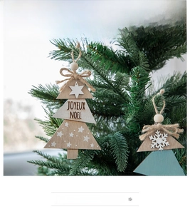 Detail of wooden Christmas tree ornament with Joyeux Noel text hanging on a branch