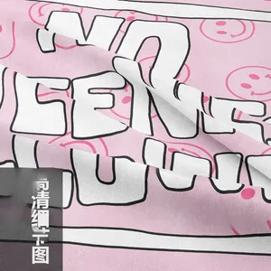 Close-up of pink fabric texture featuring white bold letters and trendy smiley patterns