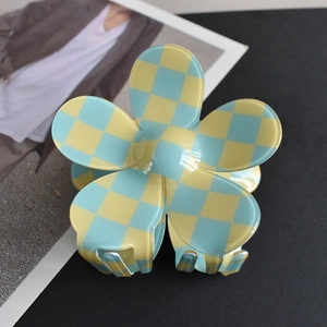 Close-up of a floral-shaped hair claw featuring a vibrant yellow and blue checkerboard pattern