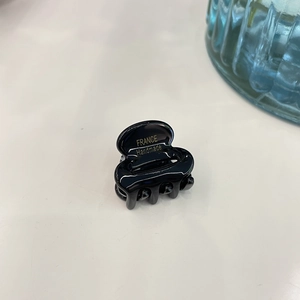 Detailed view of a small black acetate hair claw clip with France Handmade lettering